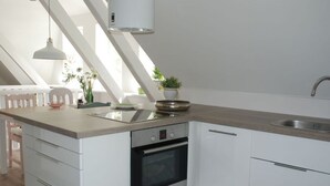 A modern kitchen with a built-in oven, a stainless steel sink, and a light-colored countertop. - Apartment at the Eichenpark (Egestorf)