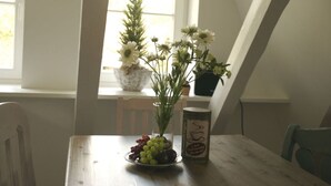 A dining table with a plate of fruit, a vase with flowers, and a canister. - Apartment at the Eichenpark (Egestorf)