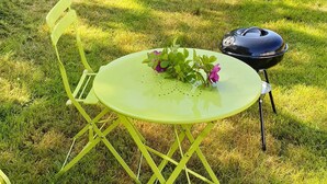 A green metal table with a plant on it, a chair, and a barbecue grill. - 8 Person Holiday Home in Nordfold-by Traum (Steigen)