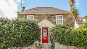 A stone house with a red door, a white window, and a grey gate. - 19th Century Cottage & Garden, Private Parking (Cornwall)