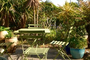 Ein grünes Tisch- und Stuhlgarnitur in einem Garten mit Topfpflanzen und einer Palme.