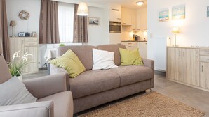 A cozy living room with a sofa, a coffee table, and a dining area with a table and chairs. - Amazing Apartment on the First Floor (Middelkerke)
