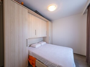 Une chambre à coucher avec un lit, une armoire en bois et un luminaire au plafond.