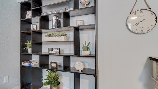A black metal shelving unit with various decorative items and a clock on the wall. - Colorado Bay A & B (Colorado Springs)