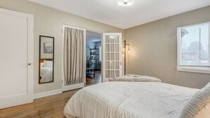 A bedroom with a large bed, a door leading to a hallway, and a window with blinds. - Colorado Bay A & B (Colorado Springs)