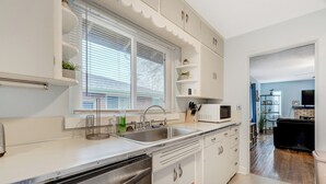 A modern kitchen with white cabinets, a stainless steel dishwasher, a double sink, and a microwave. - Colorado Bay A & B (Colorado Springs)