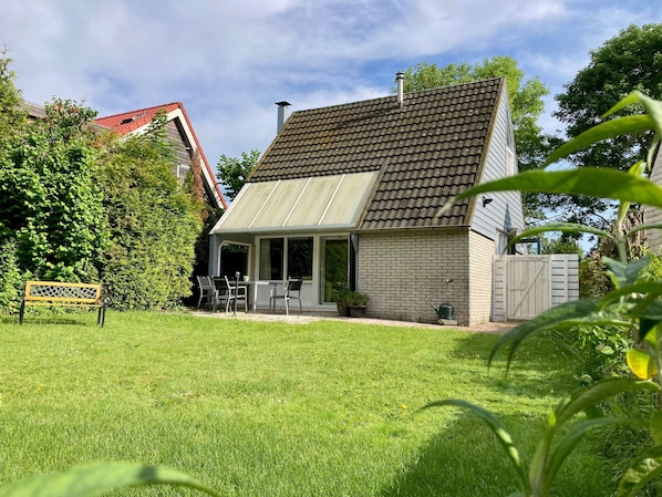 A house with a sloped roof, a covered patio, and a fenced backyard.