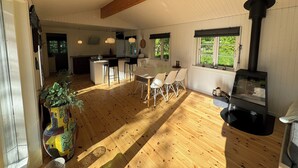 Una habitación amplia con suelo de madera, un comedor con sillas, una cocina con estufa y un gran ventanal.