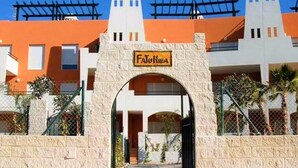 L’entrée d’un hôtel, avec une arche en pierre, une enseigne indiquant « Fajurka », et une vue sur la façade orange de l’immeuble et ses nombreuses fenêtres.