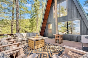 Une cabane en bois moderne dotée d’une terrasse, aménagée avec des meubles d’extérieur et une cheminée.