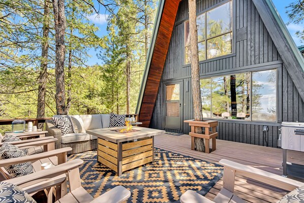 A modern wooden cabin with a deck, furnished with outdoor seating and a fireplace.