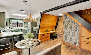 Une cuisine moderne avec un coin repas, des éléments décoratifs en bois et un lustre.
