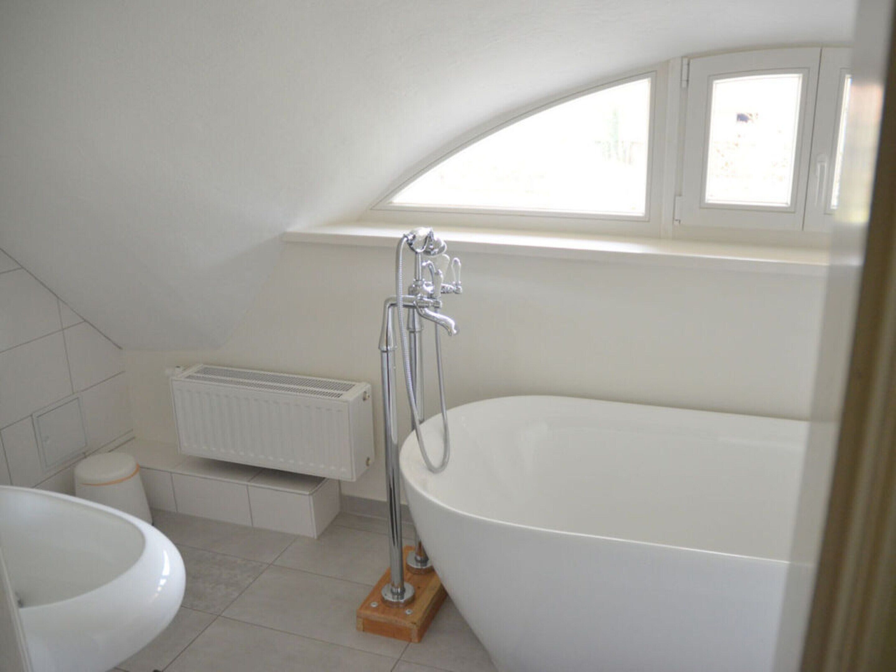 Un baño moderno con una bañera independiente, un inodoro y un radiador.