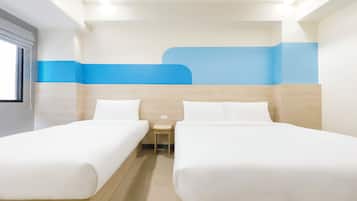 A hotel room with two beds, a small table, and a window.