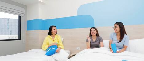 A hotel room with two beds, a large window, and a blue wall design.