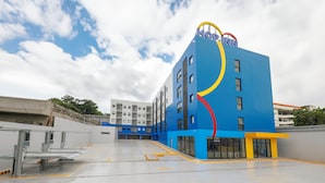 Un bâtiment moderne avec une façade bleue et un logo jaune et rouge. Il comporte plusieurs étages et de grandes fenêtres.