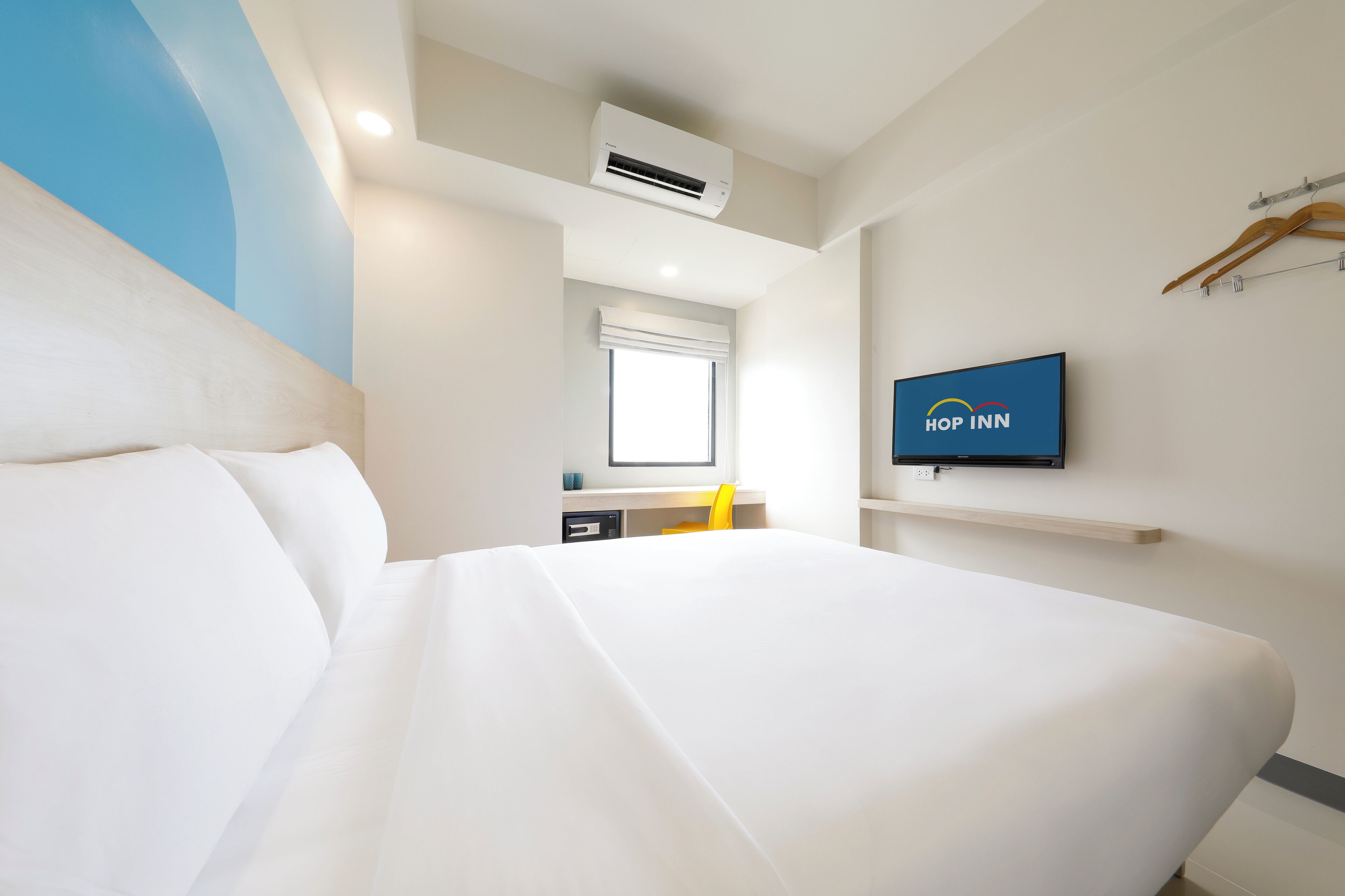 Habitación de hotel con una cama grande, un televisor montado en la pared, una ventana y un aire acondicionado.