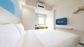 Habitación de hotel con una cama grande, un televisor montado en la pared, una ventana y un aire acondicionado.