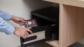 Una persona guardando un pasaporte en una caja fuerte negra con teclado numérico.