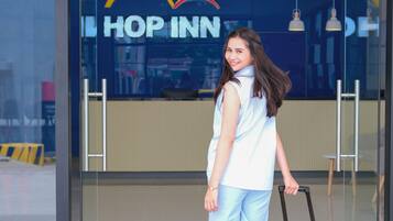 Una persona está de pie frente a la entrada de un hotel, con un cartel que dice "HOP INN".