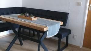A dining area with a wooden table, black metal legs, and a blue upholstered bench. - Reindler Modern Retreat (Fischen im Allgaeu)