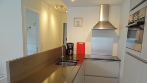 A compact kitchen with a stainless steel range hood, a coffee maker, and a red cutting board. - Apartment in Nieuwpoort Near the Beach (Nieuwpoort)