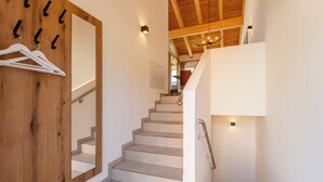 Un escalier avec un mur en bois et un miroir, menant à une pièce ornée d’un lustre.
