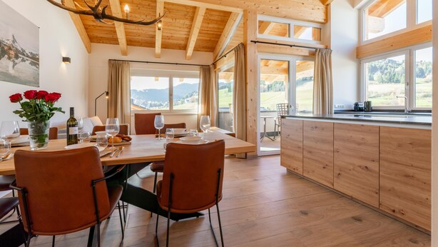 A dining area with a wooden table, chairs, and a chandelier. - Spacious home located directly at the slopes (Sankt Lambrecht)