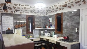 A kitchen with a central island, a stove, and various kitchen appliances. - Maison la branche d oiseaux (Douar Driss)