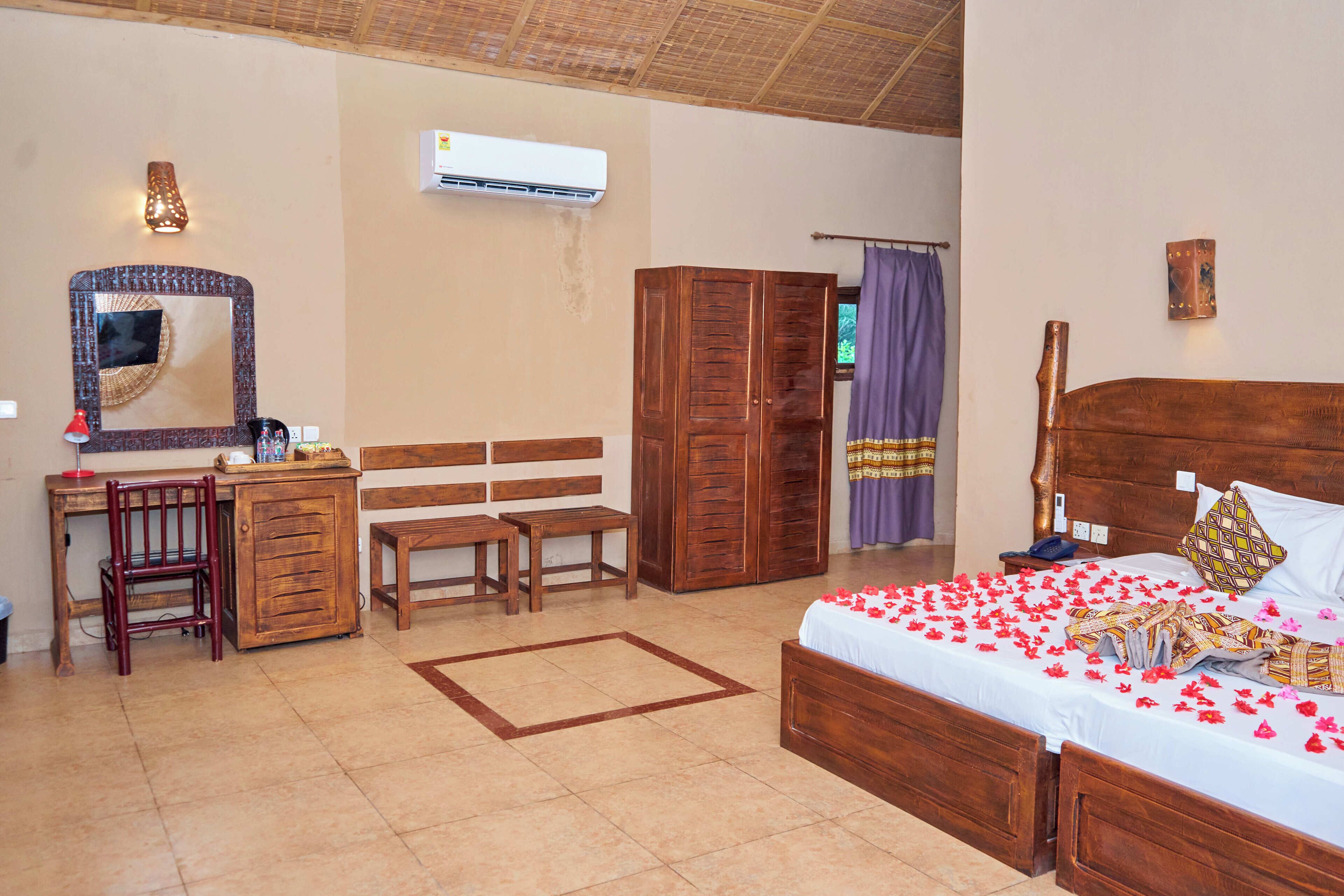 A room with a bed, desk, chair, wardrobe, and an air conditioning unit.
