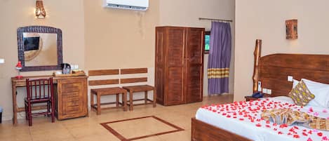 A room with a bed, desk, chair, wardrobe, and an air conditioning unit.