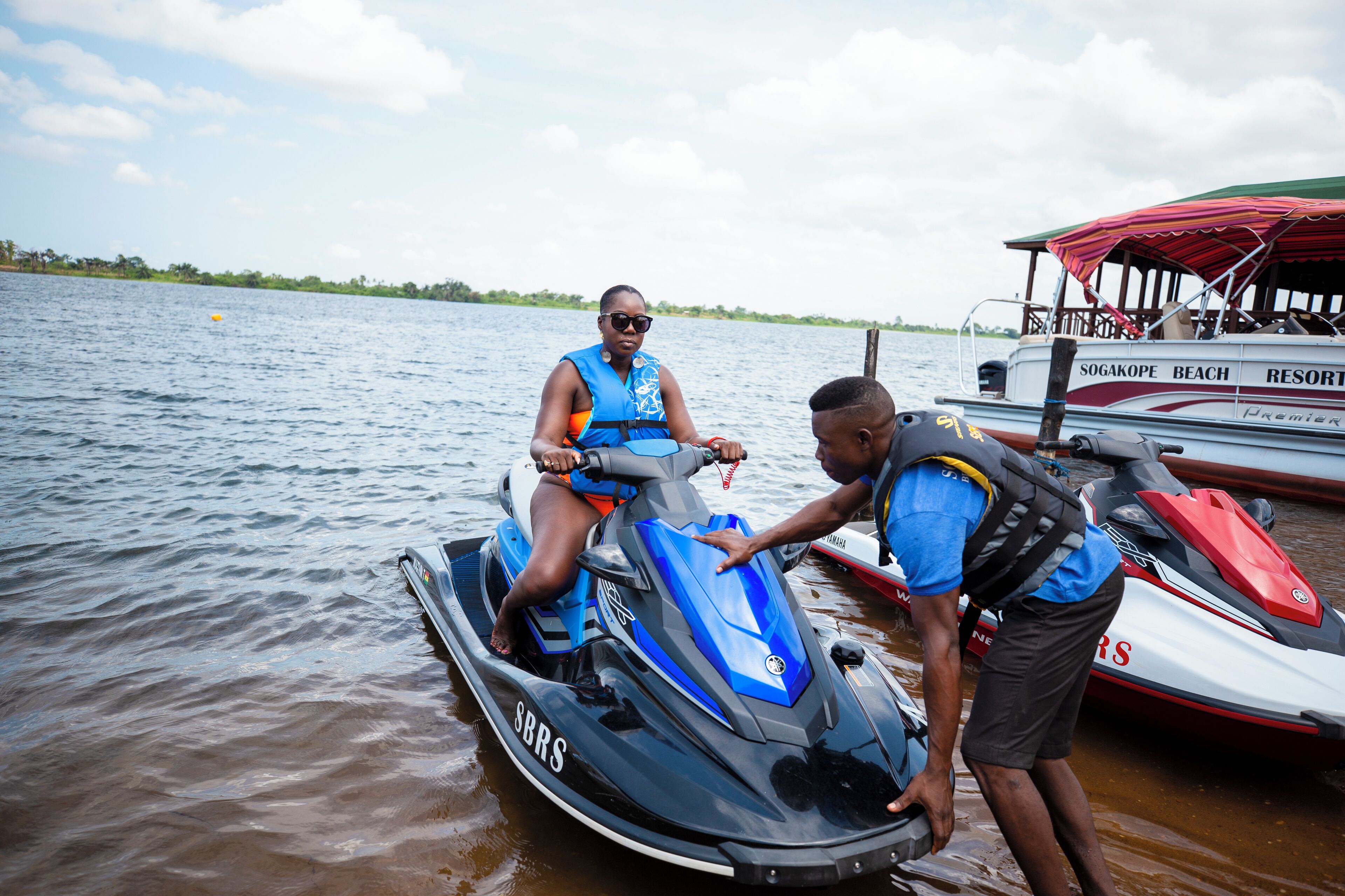 A jet ski on the water with a person on it and another person assisting.