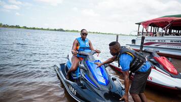 A jet ski on the water with a person on it and another person assisting.
