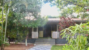 Una casa con un camino a cuadros que conduce a una entrada con portón, rodeada de abundante vegetación y diversas plantas.