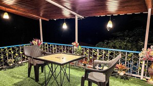 An outdoor patio with a table and chairs, surrounded by a wooden fence and potted plants. - Lsq Sunita Farms (Karjat)