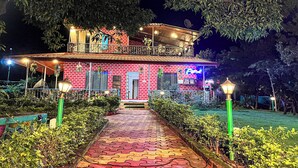 A two-story building with a red brick facade, a balcony, and a pathway leading to the entrance. - Lsq Sunita Farms (Karjat)