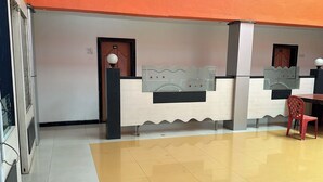A reception area with a check-in counter, a red chair, and a door marked with the number 402. - Hotel Blue Heaven (Mahabaleshwar)