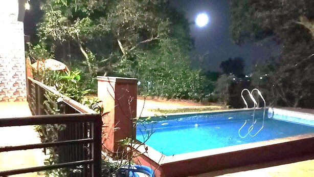 A swimming pool at night with a metal ladder and a hose coiled beside it. - Devansh Villa (Mahabaleshwar)