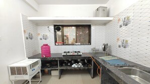 A compact kitchen with a gas stove, sink, and a window with a view. - Devansh Villa (Mahabaleshwar)