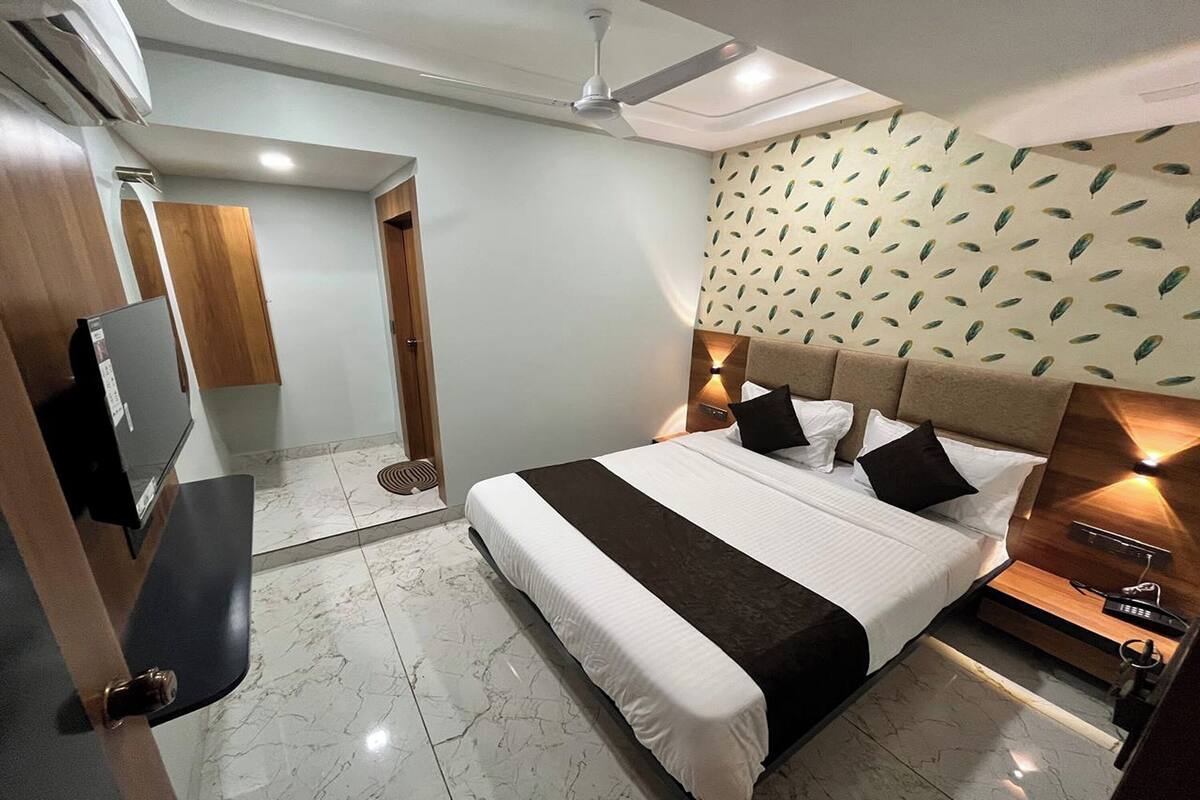 A modern hotel room with a large bed, a flat-screen TV, a ceiling fan, and a patterned wall.