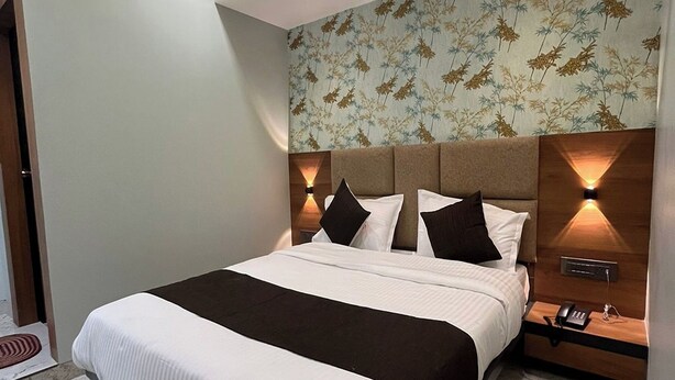 Una habitación de hotel moderna con una cama grande, un ventilador de techo y una mesita de noche con un teléfono.