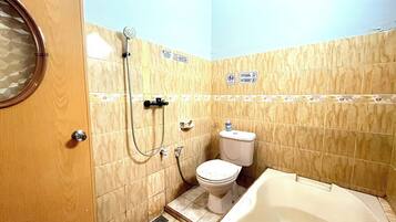 Een badkamer met toilet, douche en bad.