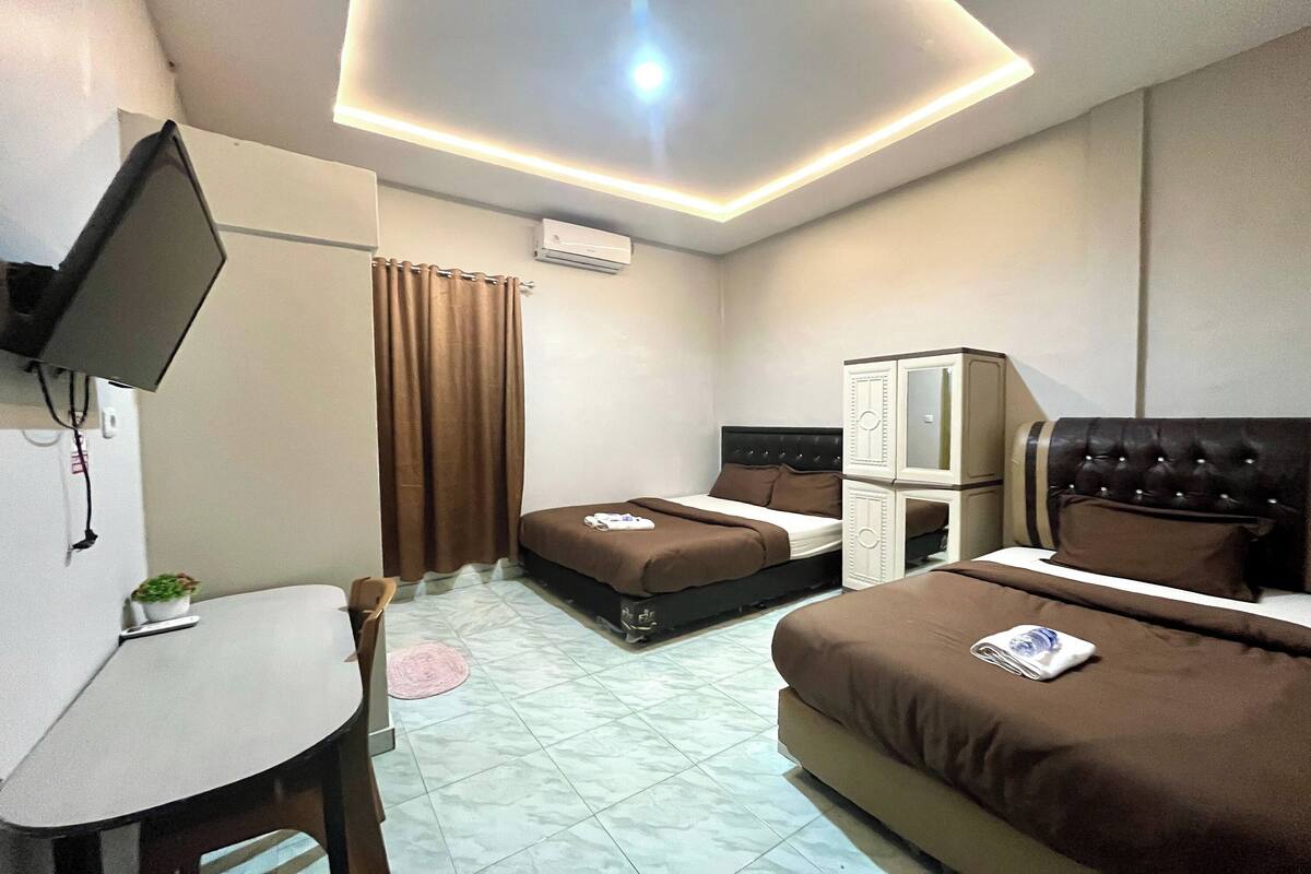 Une chambre d’hôtel équipée d’un lit, d’un bureau, d’une chaise, d’un téléviseur fixé au mur et d’un appareil de climatisation.
