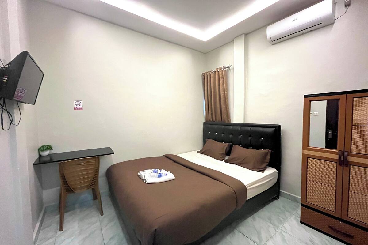 Une chambre à coucher comprenant un lit, un bureau, une chaise, une armoire et un appareil de climatisation.