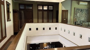 A multi-level interior with a central open space, wooden doors, and a large framed artwork on the upper wall. - R Residence Jakarta (Jakarta)