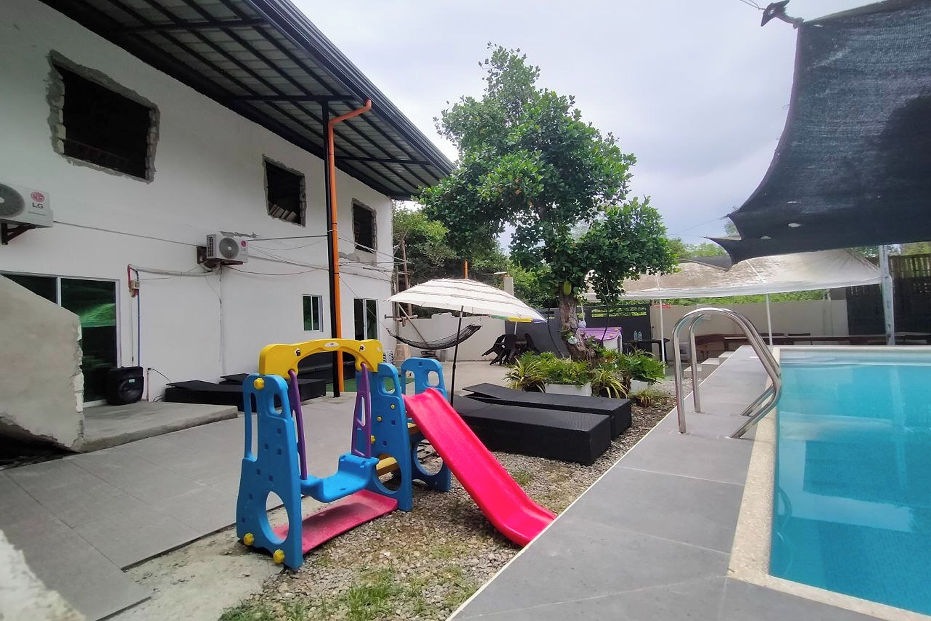 A swimming pool area with a slide, play structure, and umbrellas.