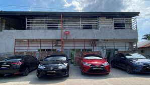 A building with a gated entrance and three parked cars in front. - Asiah'S Villa (Dauis)