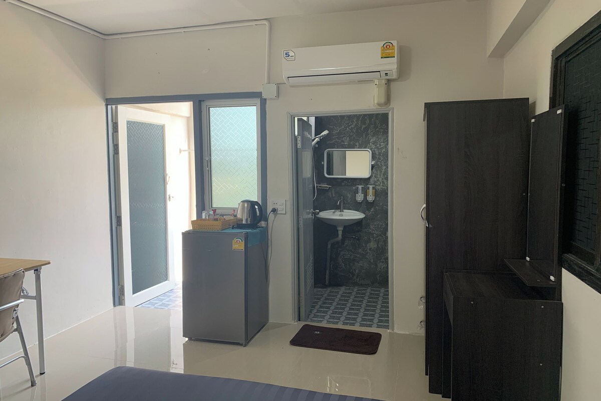 A compact room with a kitchenette, a shower, and a small seating area.