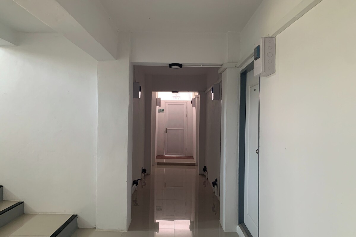 A hallway with a door at the end, a light fixture on the ceiling, and a thermostat on the wall.
