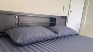 A bed with a dark headboard and two pillows. - Na Nont Place (Pak Kret)